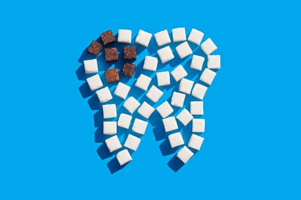 Tooth of sugar cubes on blue background