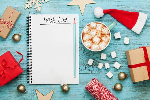 Cup of hot cocoa or chocolate with marshmallow, holiday decorations and notebook with wish list on turquoise vintage table from above, christmas planning concept. Flat lay style.