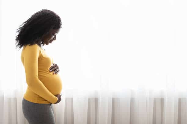 black pregnant woman holding her belly